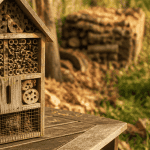 Hôtel à insectes inconvénients, modèle en bois usé sur table, alternatives naturelles en arrière-plan